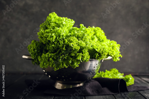 Colander with fresh lettuce on dark background