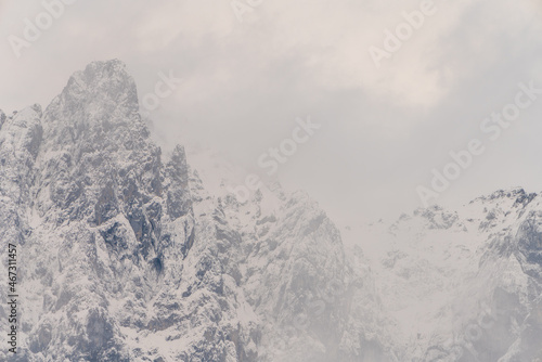 Wilder Kaiser in Tirol Österreich mit ersten Schnee im Jahr umhüllt von Wolken und Nebelschwaden.