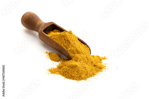 Curry powder in wooden scoop isolated on white background. Copy space