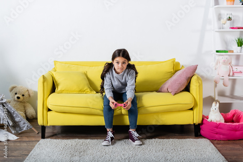 KYIV, UKRAINE - SEPTEMBER 17, 2021: tensed preteen kid playing video game at home.
