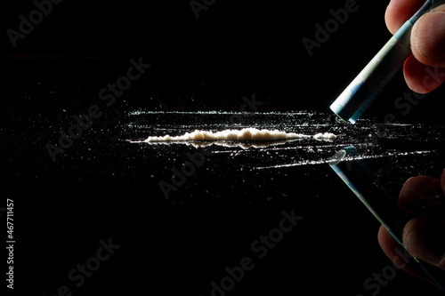 Man hands rolls banknote for using cocaine powder lines. Drug addiction concept. A line of coke on black background. Concept of addiction. Mephedrone, amphetamine, heroin. Serious addiction
