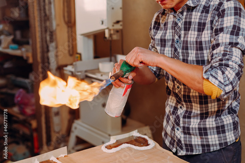 Carpenter lighting a blowtorch in a workshop