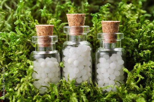 Three bottles of homeopathy globules on green moss. Bottles of homeopathic granules. Homeopathy medicine concept.