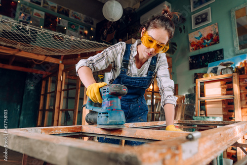 Young woman wearing protective glasses working in the workshop