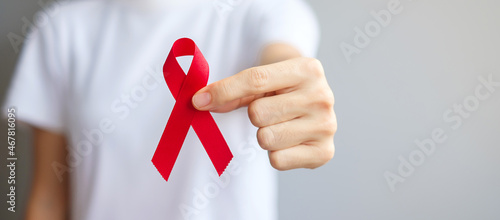 Hand holding Red Ribbon for December World Aids Day (acquired immune deficiency syndrome), multiple myeloma Cancer Awareness month and National Red ribbon week. Healthcare and world cancer day concept