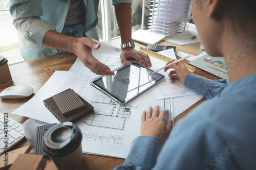 Architects and interior designers women discussing to concept of building design. Estimation for construction project with tablet technology, Drawing, Material and Model. Selective focus center image