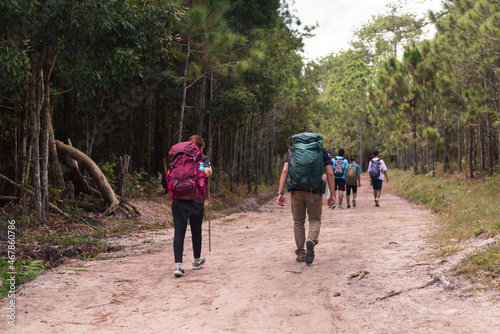 Young man and woman backpack and trekking at the mountain.Traveler walking on the adventure road in the forest.Lover on summer vacation trip in the mountains.