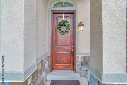 Wooden front door of a house with transom window and leafy wreath at the front