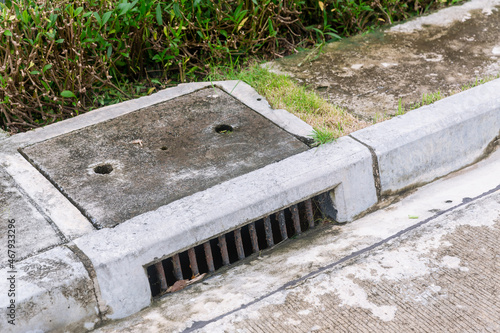 Sewer Drain along Road. A storm drain on the side of a road. Suburban street drain