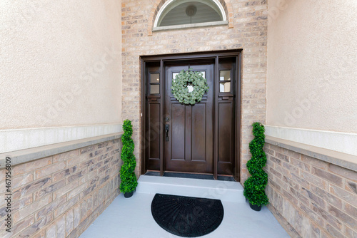 Brown front door with wreath, two side panels and arched transom window