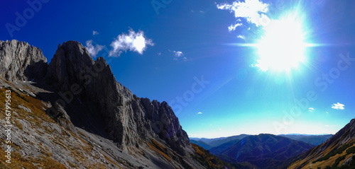 amazing mountain peaky mountain range with shining sun on the blue sky panorama