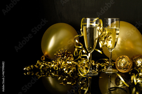 Two glasses of champagne, golden balloons and decorations. New Year's Eve celebration composition.