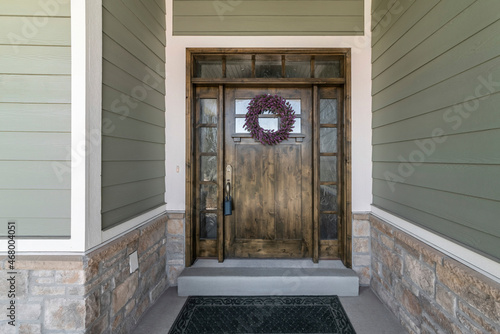 Large dark wood front door with two side panels and transom window