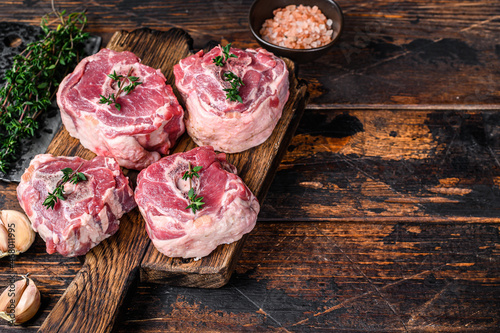 Raw mutton lamb neck meat on a butcher board with cleaver. Dark wooden background. Top view. Copy space