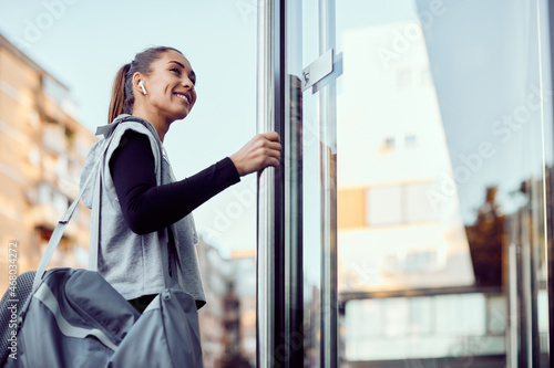 Below view of happy athletic woman entering in a gym.