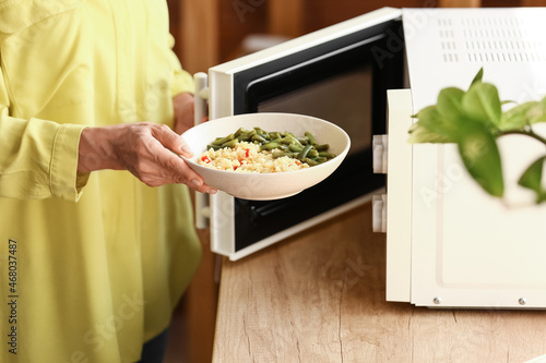 Mature woman heating food in microwave oven