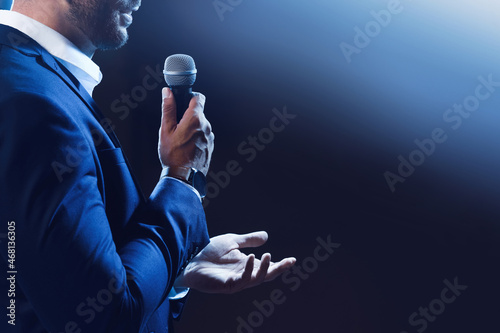 Motivational speaker with microphone performing on stage, closeup. Space for text