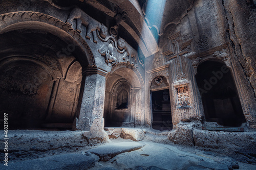 Interior of the famous Geghard Monastery and church carved into the rock. A ray of light illuminates an ancient bas-relief depicting lions in the hall