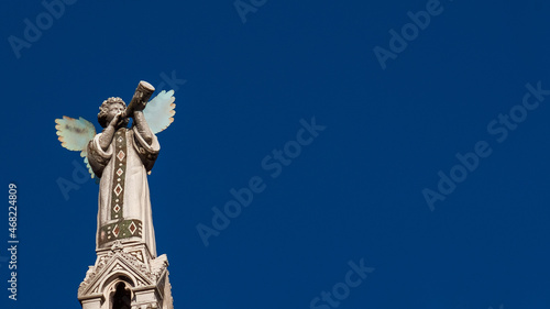 Cherub Angel blowing trumpet. A medieval 13th century statue a the top of St Michael Church in Lucca (with copy space)
