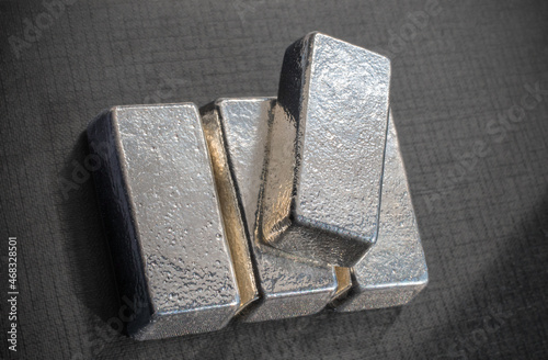 Four bullion bars of precious metal on a gray background. Platinum, palladium, pgm, silver.