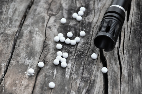 Closeup of white plastic bullets of airsoft gun or bb gun on wooden floor, soft and selective focus on white bullets.