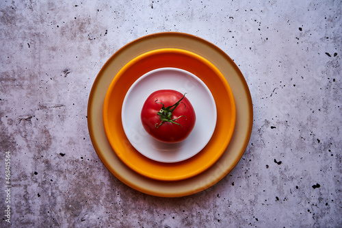 trzy talerze na betonie i pomidor