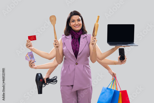 Portrait of a multitasking woman housewife with multiple hands holding various objects