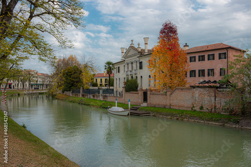 View of the Naviglio del Brenta at the town of Dolo, Italy. Autumnal image of the canal running through the city. Mysterious panorama with dramatic sky.