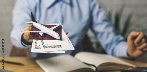 travel agent with flight tickets and plane model in hand at agency office. tourism service. copy space