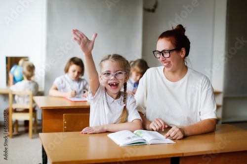 a teacher and a girl student, a child at school at a desk learning to read, a teacher and a student learn letters, working together with a teacher, with a tutor. Child and tutor in a lesson at school