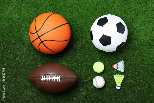 Set of different sport balls and shuttlecocks on green grass, flat lay