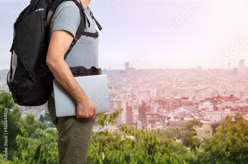 Unrecognizable digital nomad man traveling the world working with his laptop with a background city