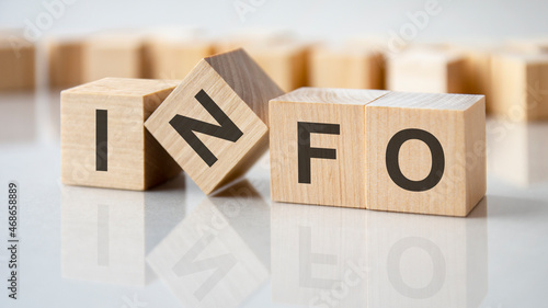 four wooden blocks with the letters info on the bright surface of a gray table, business concept
