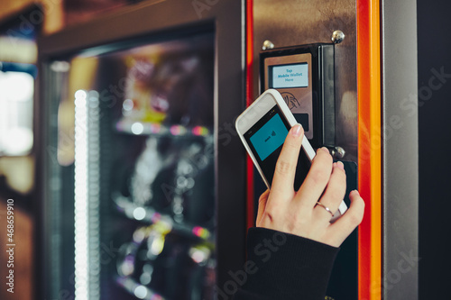 Woman paying for product at vending machine using smartphone