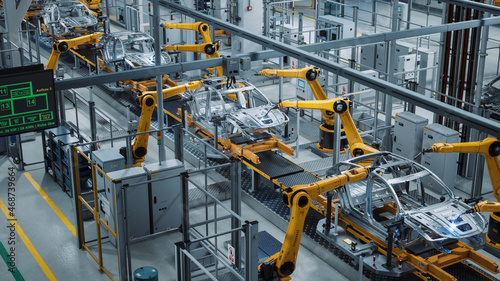 Car Factory 3D Concept: Automated Robot Arm Assembly Line Manufacturing High-Tech Green Energy Electric Vehicles. Construction, Building, Welding Industrial Production Conveyor. Elevated Wide Shot