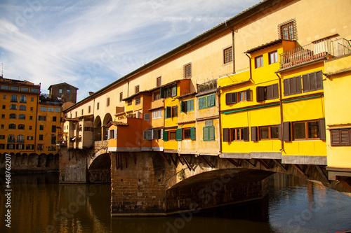 View of the Ponte Vecchio - Old Bridge - in Florence (Firenze) - by the river Arno with blue sky and reflections in the water. Famous landmark in Tuscany, Italia.