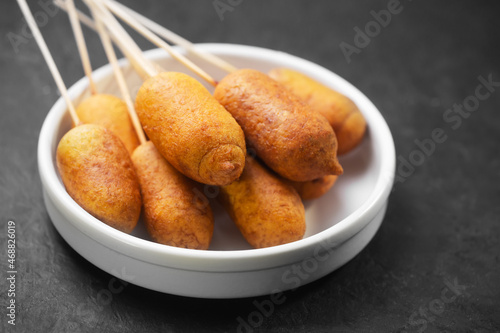Corn dogs cooked with sausage and dough on a dark background