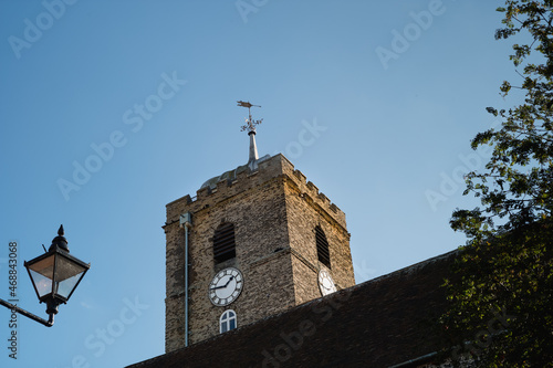 St Peters Church tower and clock lit by sunlight with a vintage street lamp in the foreground in Sandwich, Kent, uk