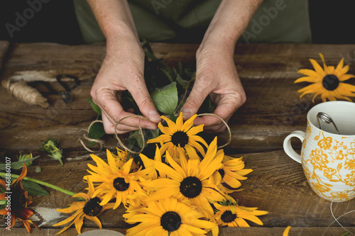 Woman's hands tying twine on bouquet of yellow flowers