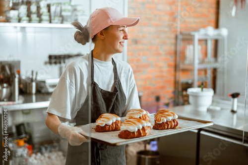 Pretty woman baker holds beautiful croissants with burnt albumenous cream in shop