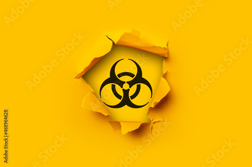 Bright yellow torn paper cardboard inside in a hole sign of radiation on a yellow background.