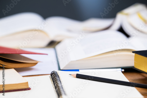 Closeup pencil on the notebook with many opened books on the desk, editing or rewrite the information from many reference book to create a new content