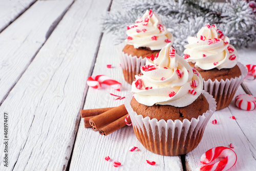 Christmas candy cane cupcakes with creamy frosting. Close up on a rustic white wood table background with copy space.