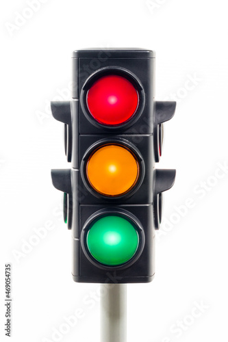 Vertical view of a traffic light showing illuminated red, amber, and green lights. Concept image illustrating control of the COVID pandemic and confusion.