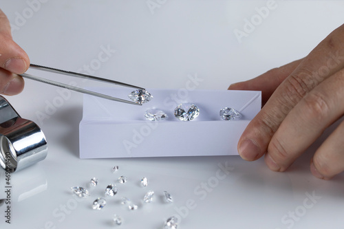 Close up of diamond expert's hand at workplace evaluating gemstones polished diamonds. High quality photo