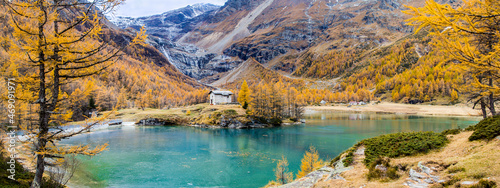 Panorama of the Palu Lake below Piz Palu glacier in Swiss Alps in autumn day with larch forest around and Piz Palu at the background, Canton of Grisons, Switzerland