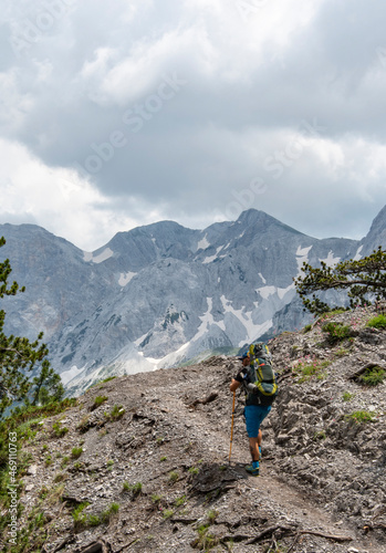 Mężczyzna idący po górach z plecakiem. Trekking w górach z plecakiem. 