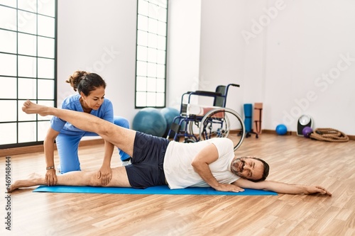 Middle age man and woman concentrate having rehab session stretching at physiotherapy clinic