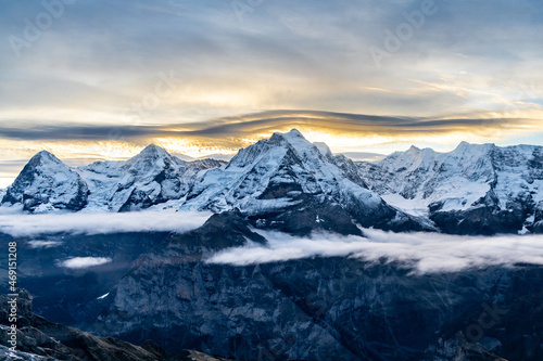 View of the famous peaks Jungfrau, Mönch and Eiger from the mountain Schilthorn in the Swiss Alps Switzerland at sunrise with dramatic clouds and fresh snow.