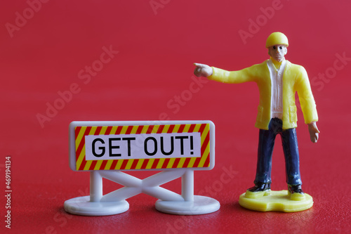 Toy man gestures aggressively next to a Get Out warning sign. The concept of prohibition of access, expulsion and deportation